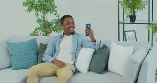 Enthusiastic Man Enjoying Video Call on Couch