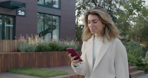 Cheerful Bussinesswoman Using Smartphone While Walking at City Street. Crop View of Stylish Woman