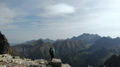 Drone Flying Over Young Woman Hiker With Backpack Walking up on Top of a Rock