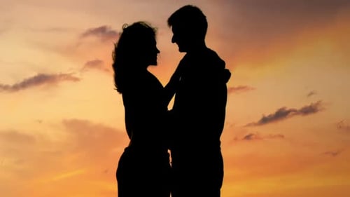 Couple Silhouetted Embracing and Kissing at Sunset