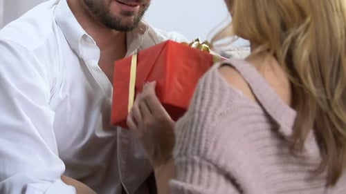 Man Giving Gift to Woman, Hugging Indoors