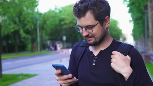 Handsome Man in Glasses Using Smartphone on the Street