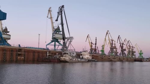 The Large Cranes at the Sea Port on Sunset Sky Background