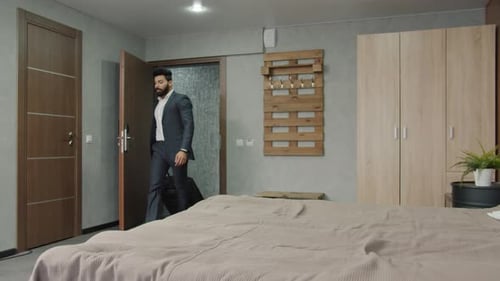 Young Arab Businessman Entering Hotel Room with Suit Lying in Bed Relaxing