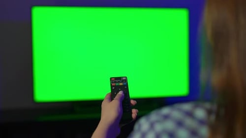 Woman Holding Remote Control in Front of Green Screen TV