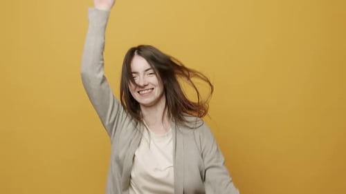 Happy Woman Dancing Energetically in Front of Yellow Backdrop