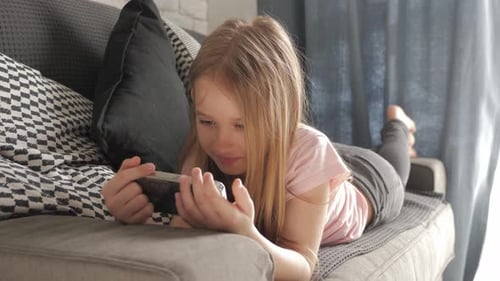 Girl Lying on Couch Playing with Smartphone