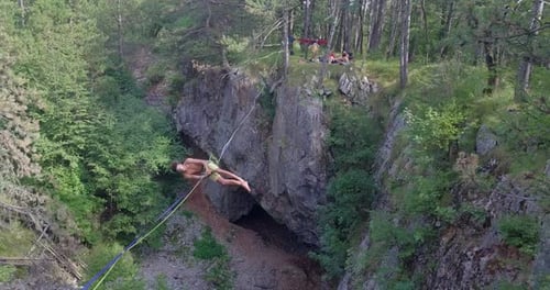 Un hombre cae mientras está holgazaneado en una cuerda floja en las montañas