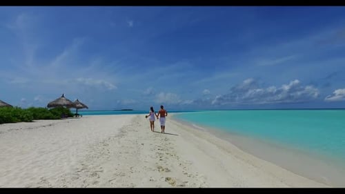 Two people happy together on perfect seashore beach time by blue green ocean with white sandy backgr
