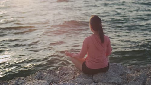 Woman Meditating By the Ocean at Sunset