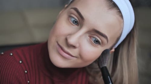 Woman Applies Makeup with Brush in Close-up