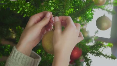 Decorating Christmas Tree with Gold Bauble Ornament
