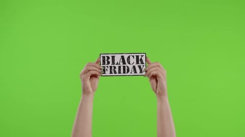 Black Friday Advertisement Inscription on Paper Sheet in Womans Hands on Chroma Key. Slow Motion