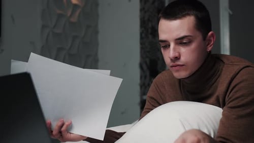 Young Adult Lying on Bed Working on Laptop