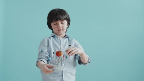 Boy Smiles While Holding a Solar System Model