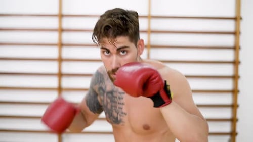 Young man boxing workout in an gym wearing red gloves