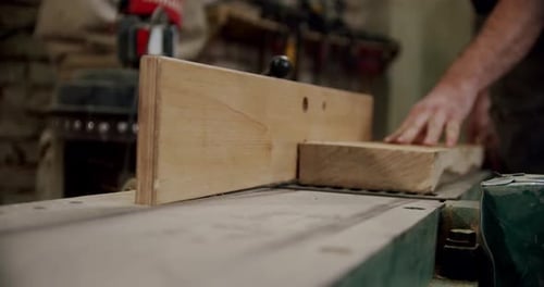 Worker in a Woodworking Workshop Takes a Board and Puts It on a Machine in Woodworking Workshop of a