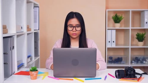 Smiling Woman Working on Laptop in Modern Office