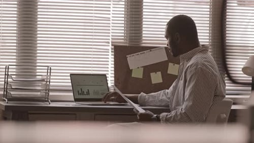 Adult Man Reviews Data At Desk