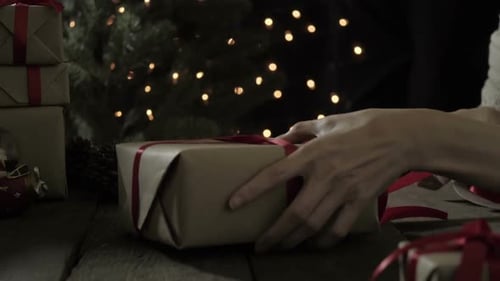 Hands Tying Red Ribbon on Christmas Present