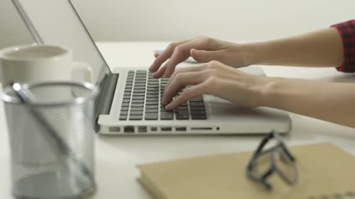 Typing on Laptop Keyboard at White Desk