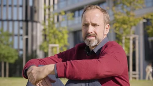 A Middleaged Handsome Caucasian Man Looks Seriously at the Camera As He Sits in a Street