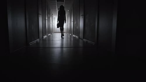 Silhouetted Woman Walking Down Dark Hallway at Night