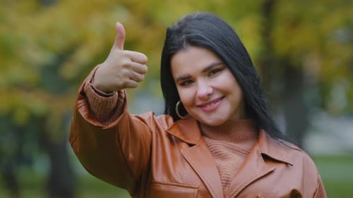 Brunette Woman Gives Thumbs Up in Fall Park