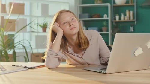 Tired Teenage Schoolgirl While Studying Online at a Laptop
