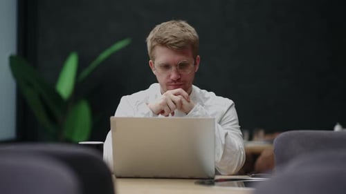 Businessman is Reading News in Internet By Laptop in His Modern Office Thinking and Planning
