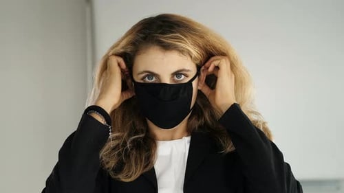 Woman Puts on Protective Face Mask Indoors