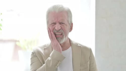 Senior Man With Toothache Holds Face In Pain