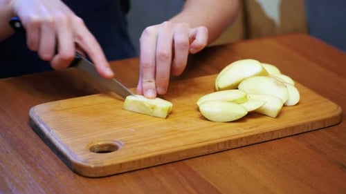 Young Adult Slicing Apple on a Wooden Cutting Board