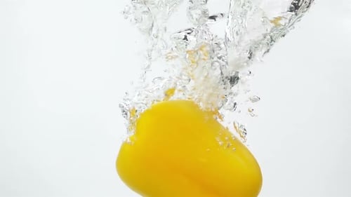 Reifer gelber Pfeffer fällt durch Wasser