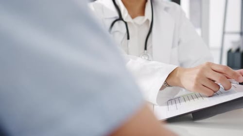 Doctor Discussing Medical Chart With Patient in Office