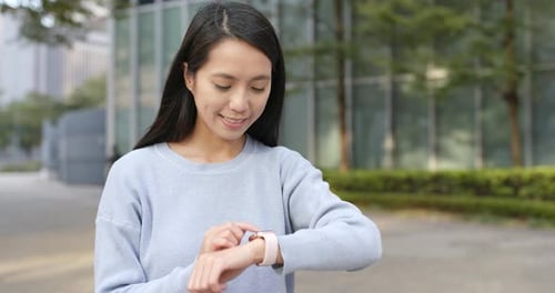 Smiling Woman Using Smartwatch in Urban Setting