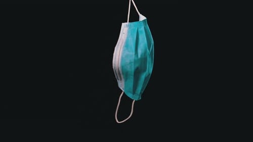 Surgical Mask Hanging Against Black Background