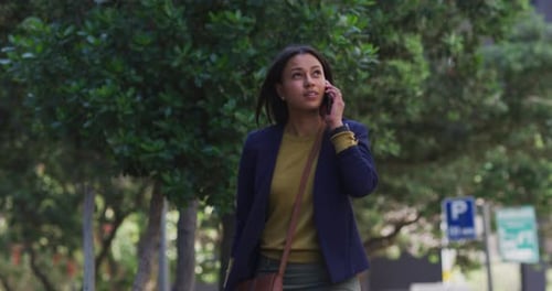 African american woman talking on smartphone while walking in street