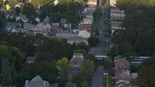 Vista aérea de casas y árboles a los lados de la calle y el tren que pasa por la ciudad