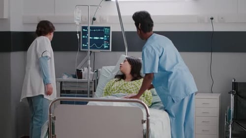 Healthcare Staff Attending to Patient in Hospital Bed