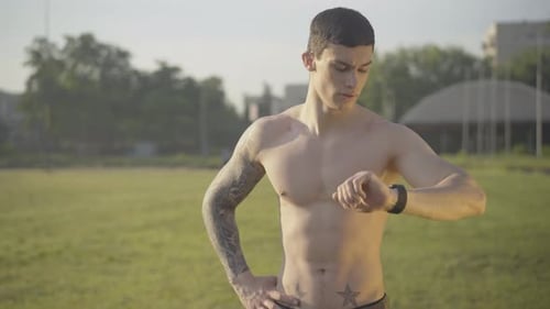 Shirtless Man Checking Time on Watch Outdoors