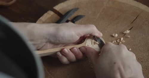 Woman Carpenter Carves Piece of Wood Making a Spoon Close-up
