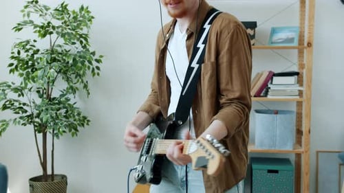 Young Adult Playing Electric Guitar at Home