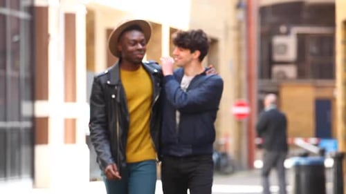 Multiracial gay couple walking embraced in London, talking and having fun tog