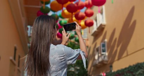Woman Takes Photo of Colorful Lanterns in City