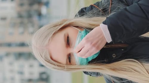 Young Woman Putting a Medical Mask on Her Face on the Street