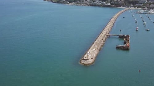 Beautiful aerial shot of a light house at the end of a pier.