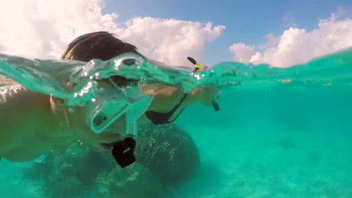A man and woman couple snorkeling over the coral reef of a tropical island.
