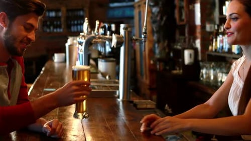 Bartender Serving Young Man a Beer at the Bar