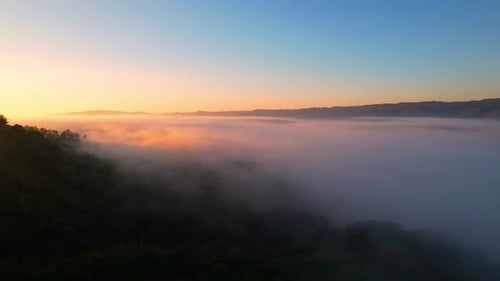 4K Aerial view from drone over mountains and sea of fog. Golden scenery at sunrise